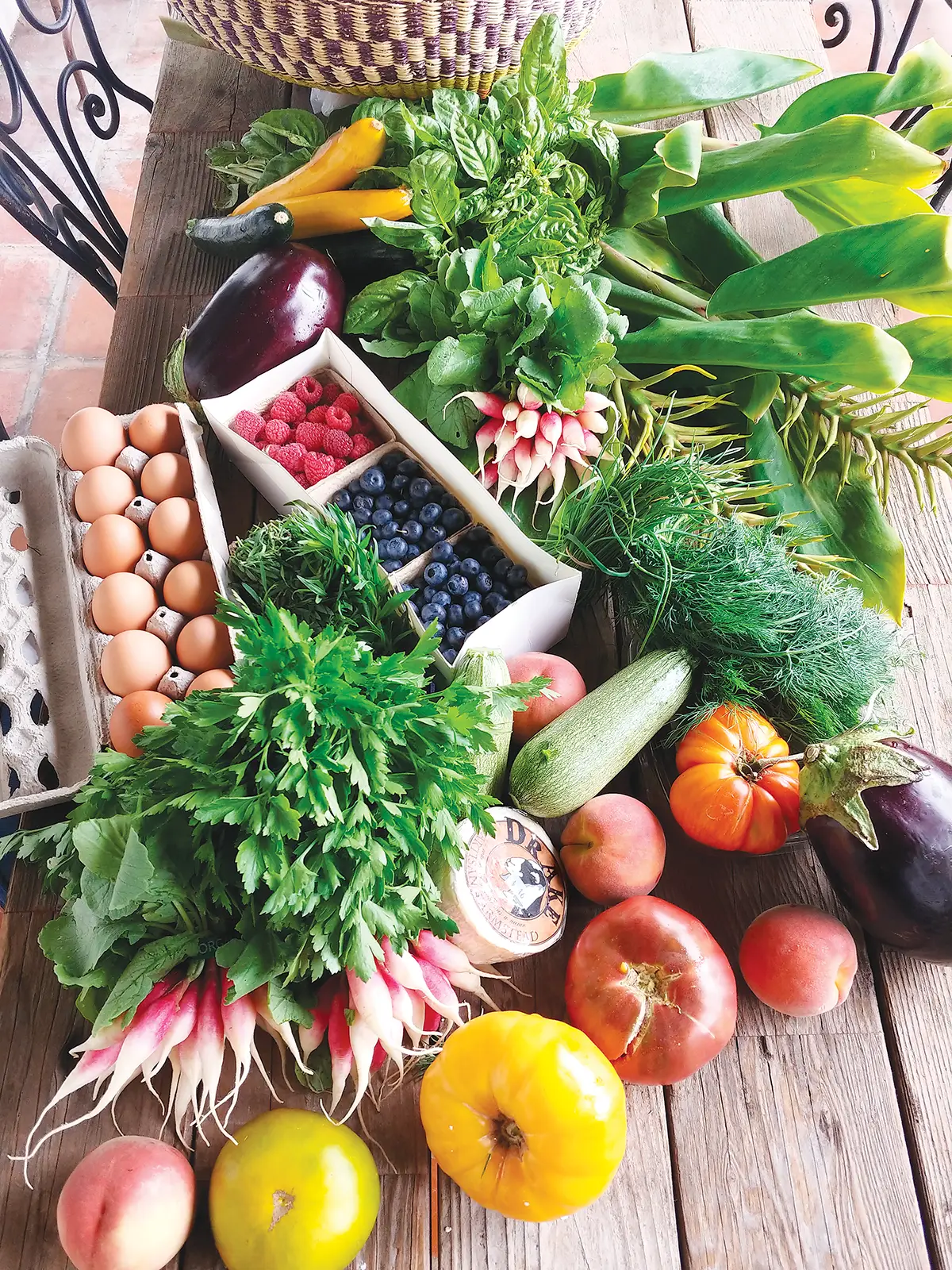 Eggs and fresh produce from the farmers market laid out on a table.