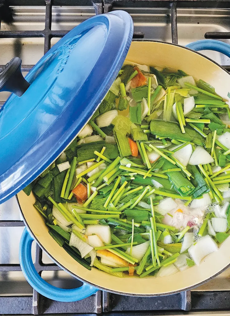 Vegetable stock in a blue stock pot on the stove.