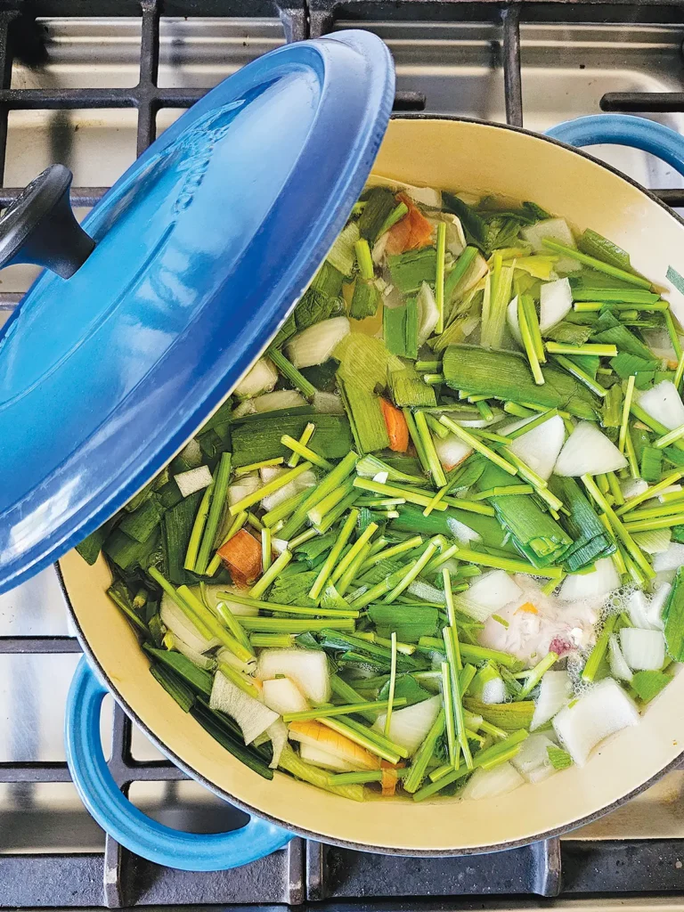 Vegetable stock in a blue stock pot on the stove.