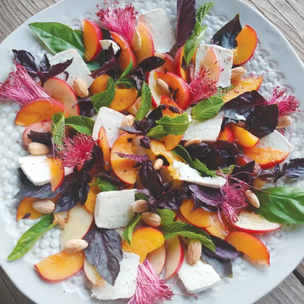 Plated peach salad set on a wooden table.