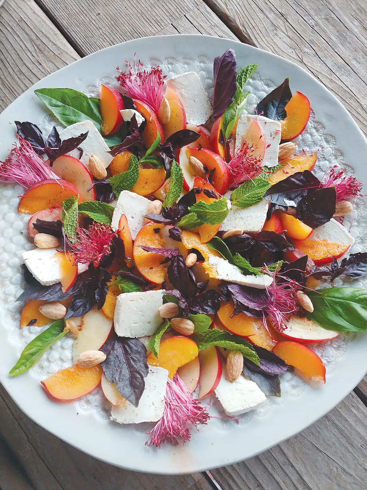 Plated peach salad set on a wooden table.