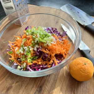 A bowl of colorful prepped ingredients about to become the red cabbage salad with citrus dressing.