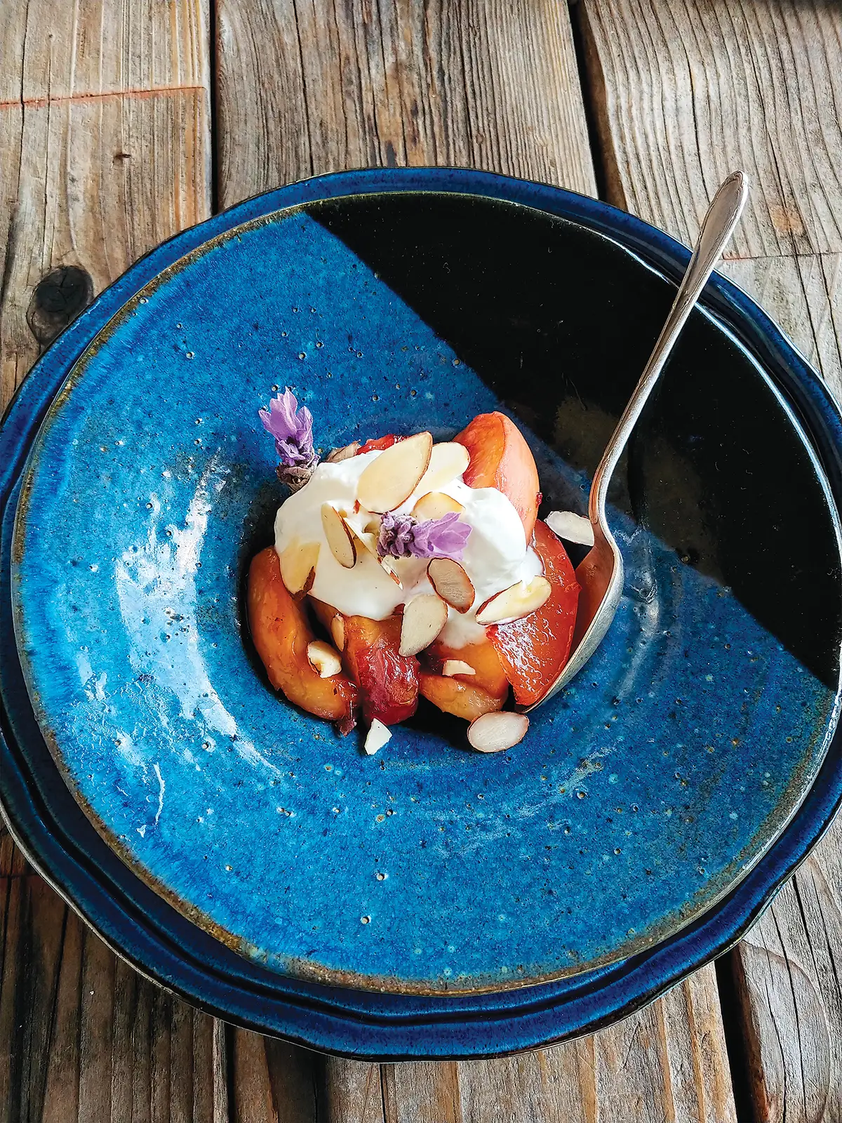 A blue bowl of Roasted White Peaches with Lavender and Crème Fraîche