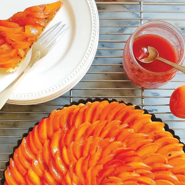 Sunflower apricot tart with a slice of the tart on a plate.