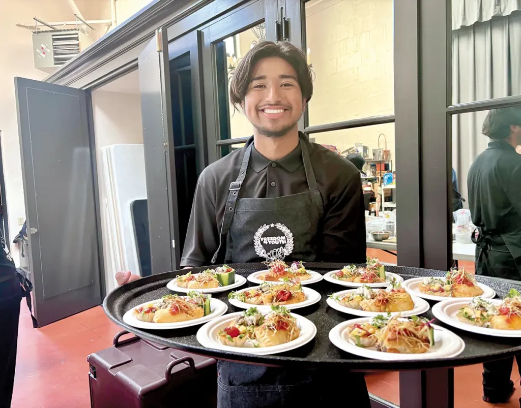 Culinary program student catering an event at the Lobero Theatre, smiling over his delicious tray of hors d’oeuvres.