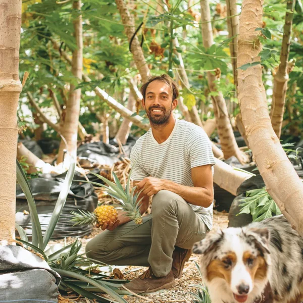 Damien "Papaya Man" Raquinio kneeling and holding a pineapple.