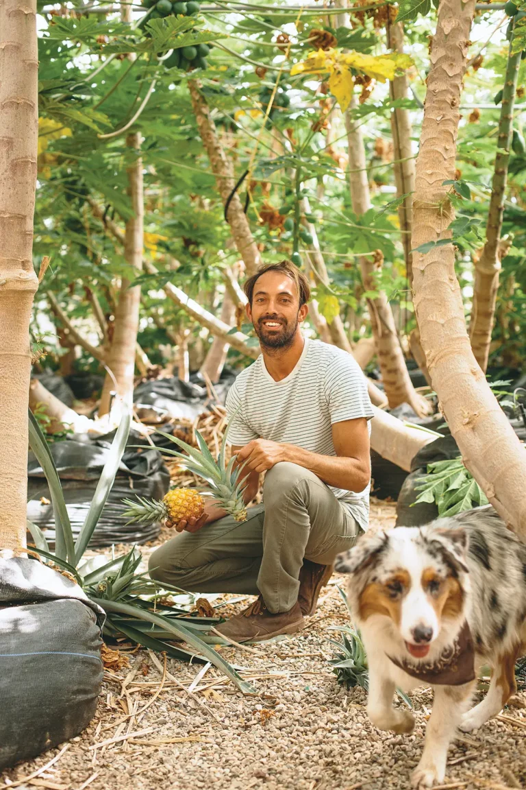 Damien "Papaya Man" Raquinio kneeling and holding a pineapple.