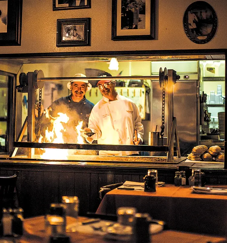 Frank and Bill Ostini behind the grill at the original Hitching Post I in Casmalia.