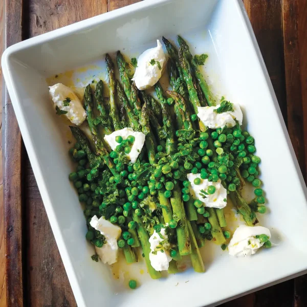 A white rectangular dish containing Grilled Asparagus with Spring Peas, Burrata and a Lemon-Mint Vinaigrette.