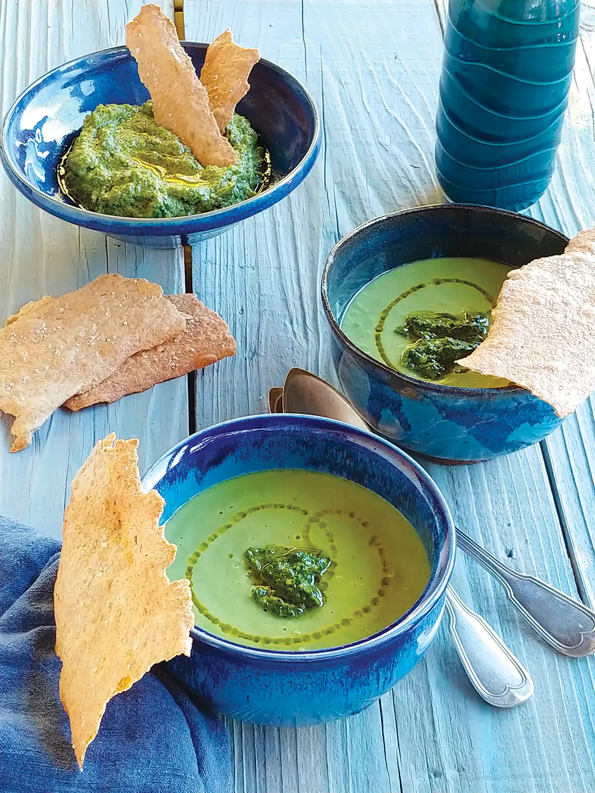 Bowls of Spring Pea and Leek Soup with Pesto on a wooden table top.