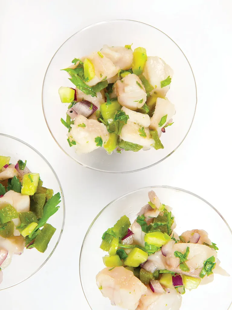 Three clear bowls containing ceviche set on a white tablecloth.