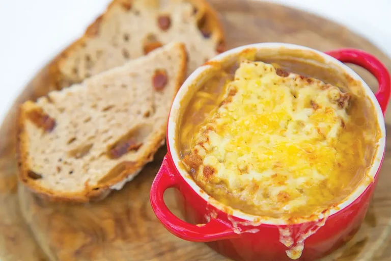 A bowl of French onion soup with two slices of bread.