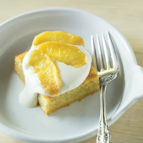 Slice of apple honey cake with marshmallow topping in a white bowl.