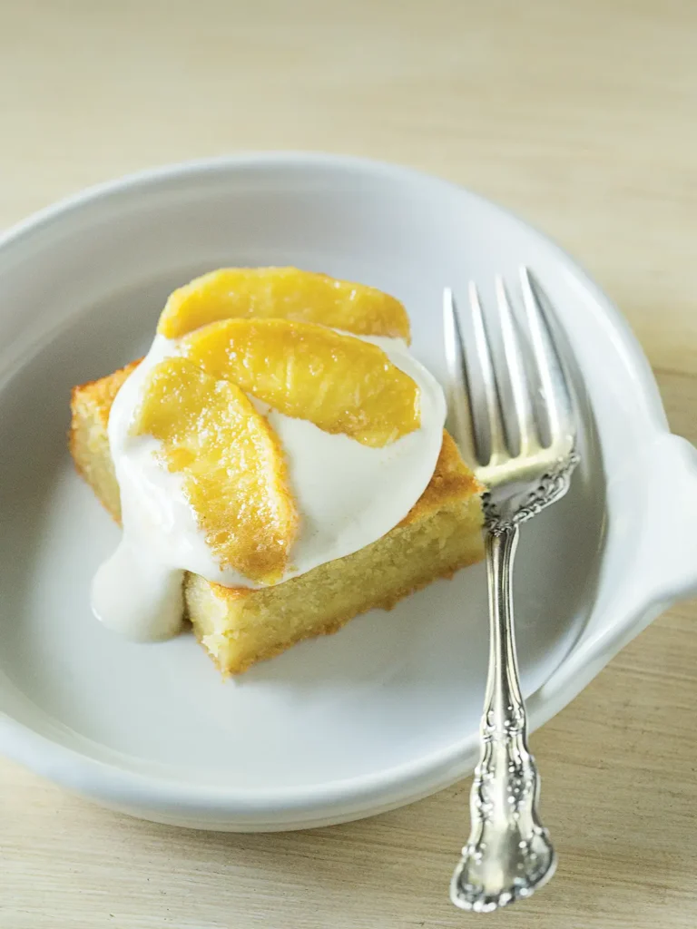 Slice of apple honey cake with marshmallow topping in a white bowl.