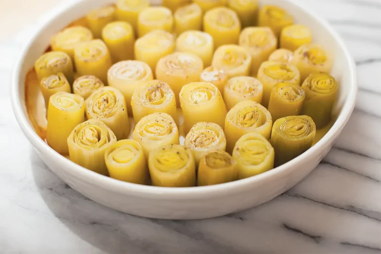 Round white dish containing cut sections of leeks arranged like cylinders in the dish.