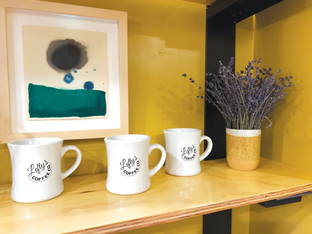 A bookshelf with three coffee mugs from Lefty’s Coffee Co. in Los Olivos.