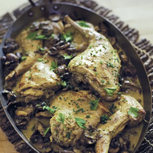 Roasting pan with rabbit in a mushroom and mustard sauce.