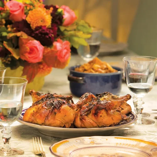 Table setting with flowers and Roasted Cornish Hens with Mushrooms and a Riesling Sauce.