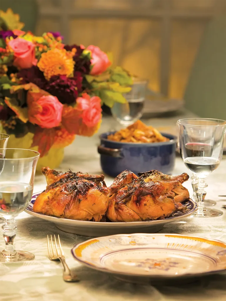 Table setting with flowers and Roasted Cornish Hens with Mushrooms and a Riesling Sauce.