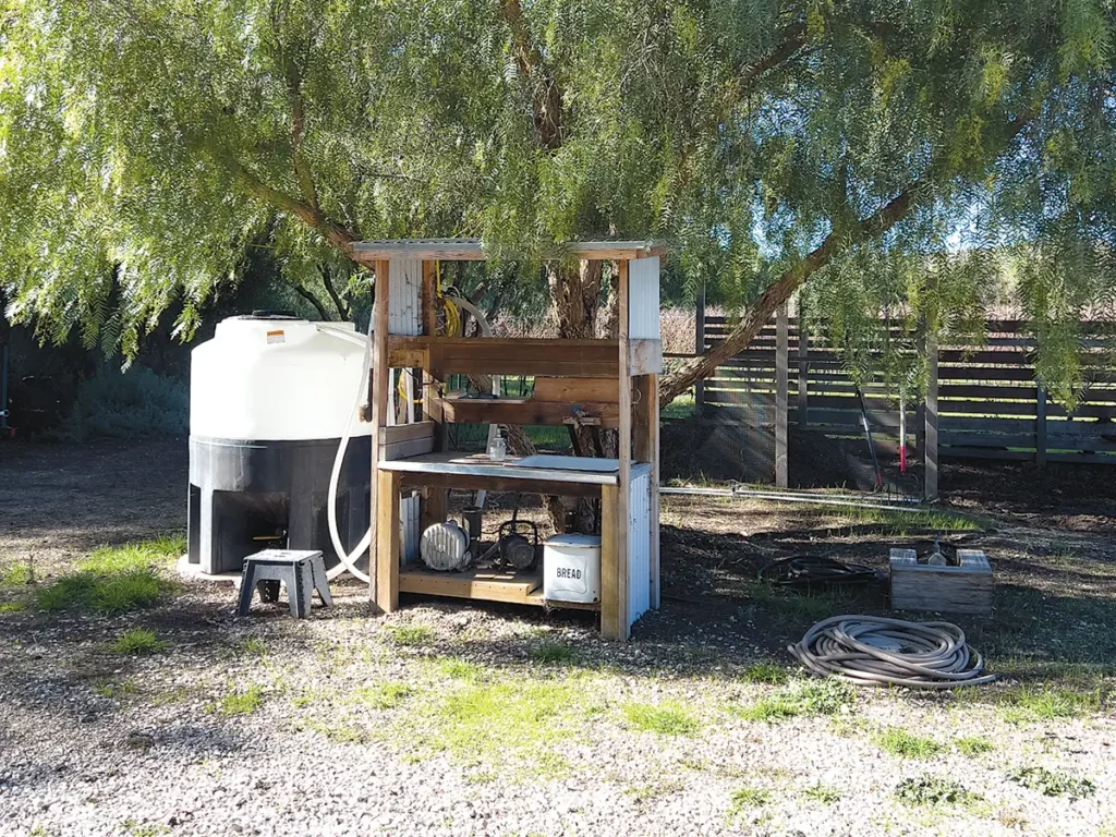 A worm tea maker under a tree.