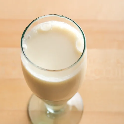 A glass of almond milk on a maple table.