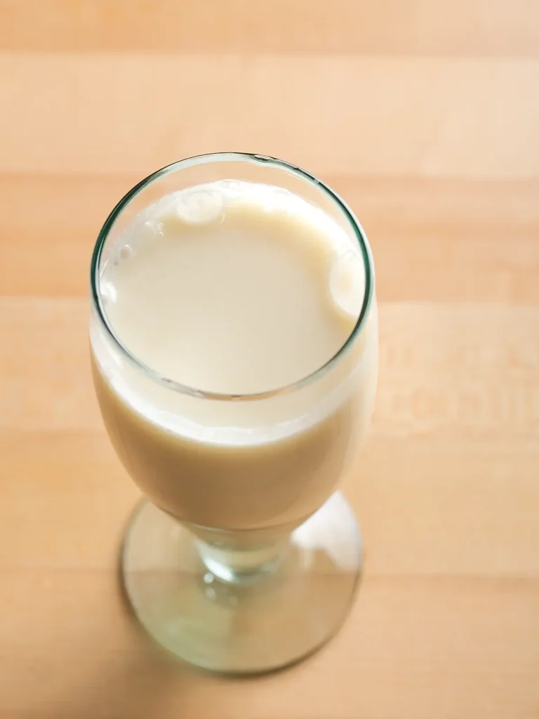 A glass of almond milk on a maple table.