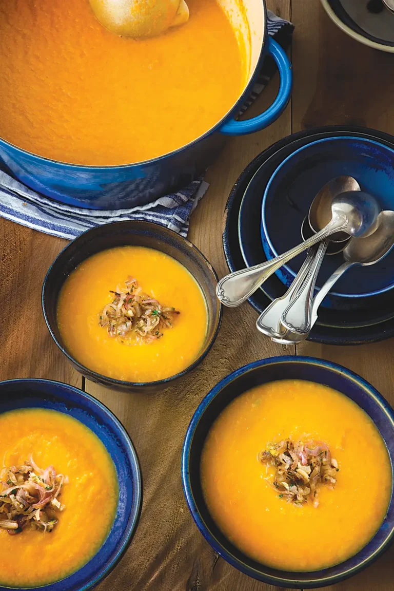 Tablescape with bowls of carrot and leek soup with zesty shallots.