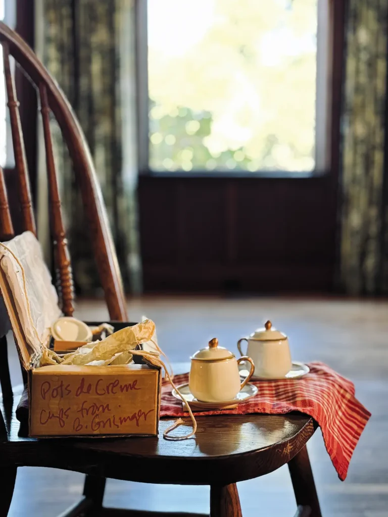 Wooden chair with a crate of pots de creme and two additional pots on the seat.