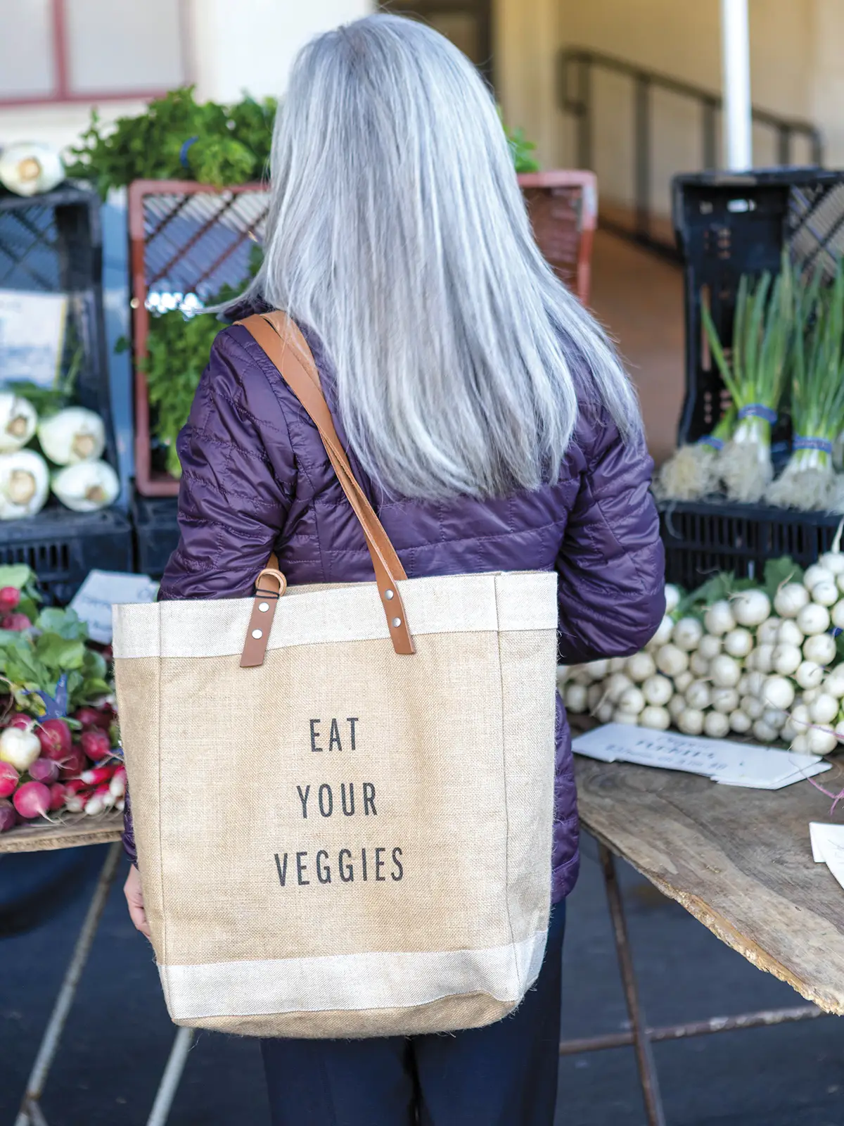 Woman with a market bag that says "Eat Your Veggies"