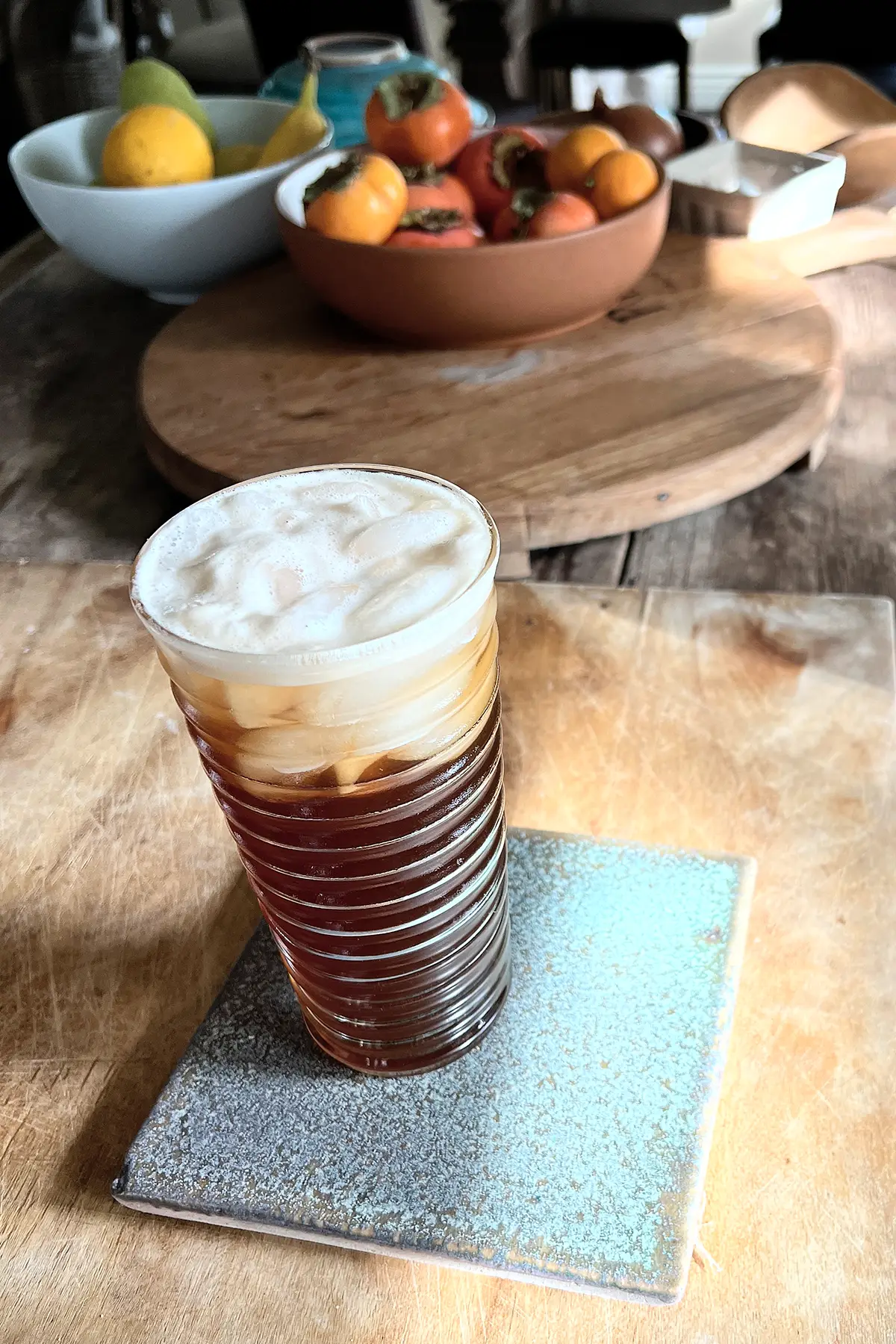 A glass of espresso ginger soda on a wooden cutting board.