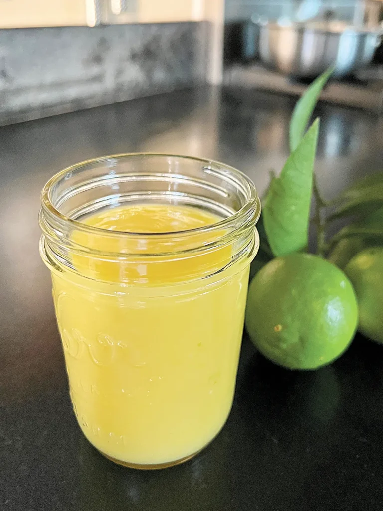 A half pint mason jar of lemon lime curd with a whole lime next to it.