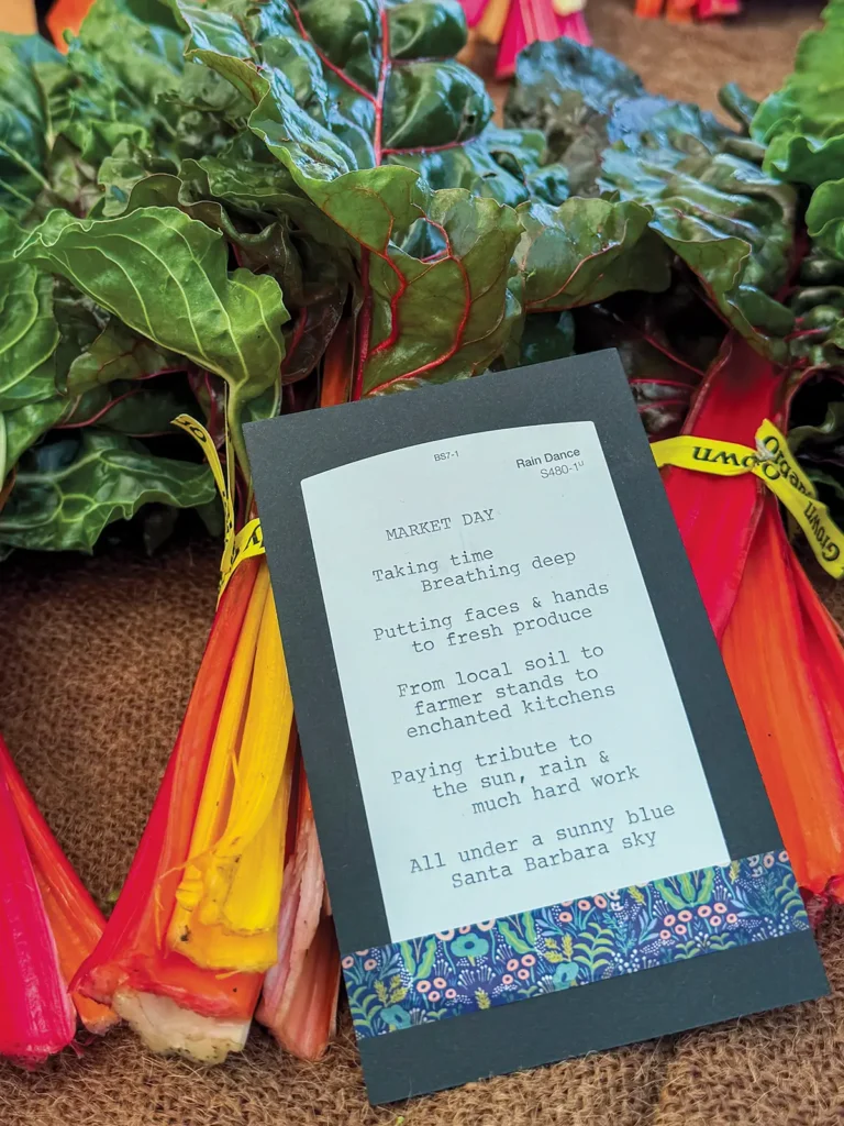 Postcard with a poem typed at the Satruday Farmers Market set on a table full of chard.