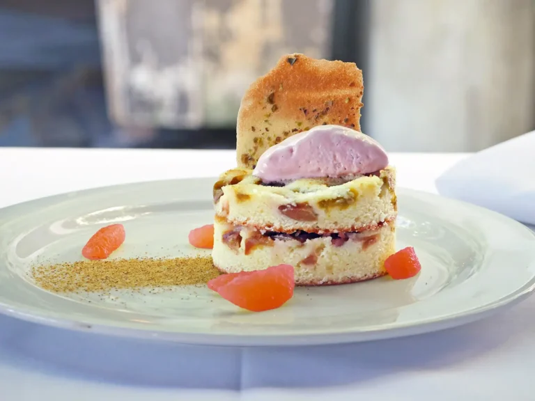 Rhubarb Upside Down Cake with Blood Orange Semifreddo and Pistachio Tuile on a white plate at Bouchon.