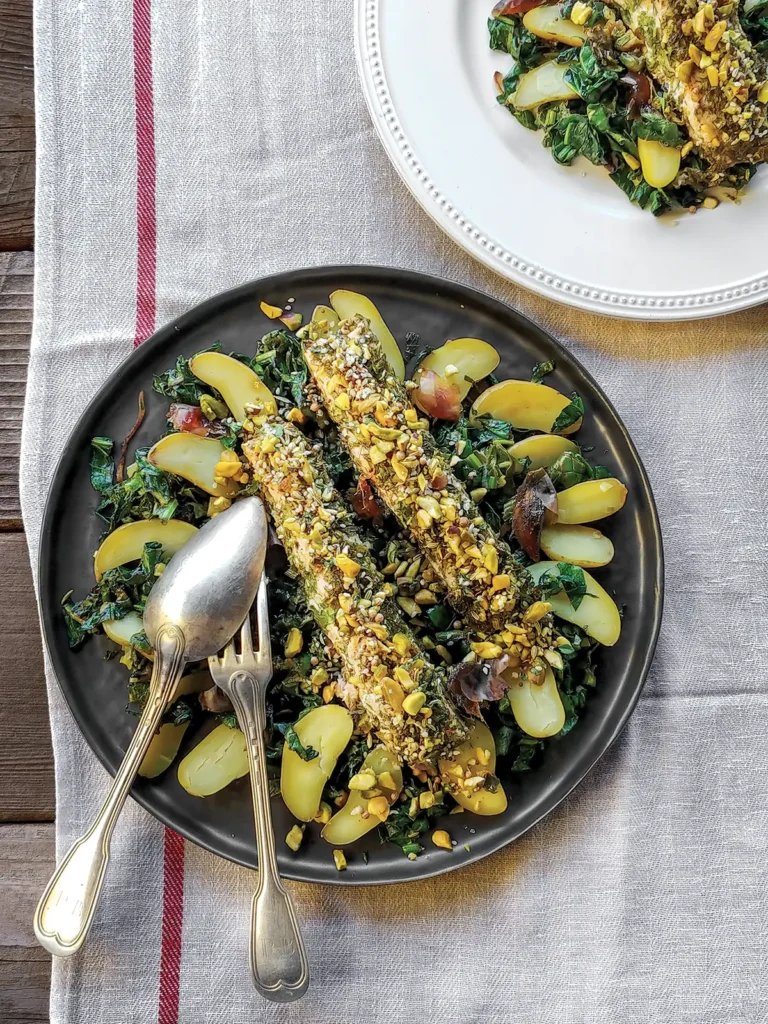 Plates of slow roasted salmon and pistachio dukkah with warm spinach and potatoes on top of a linnen cloth.