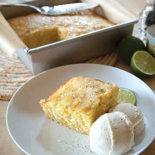 9x9 pan containing sweet corn cake with a slice removed and plated with two scoops of vanilla ice cream.