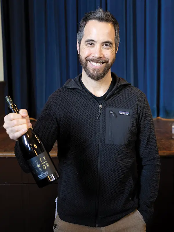 Dusty Nabor of Dusty Nabor Wines holding a bottle of his wine.