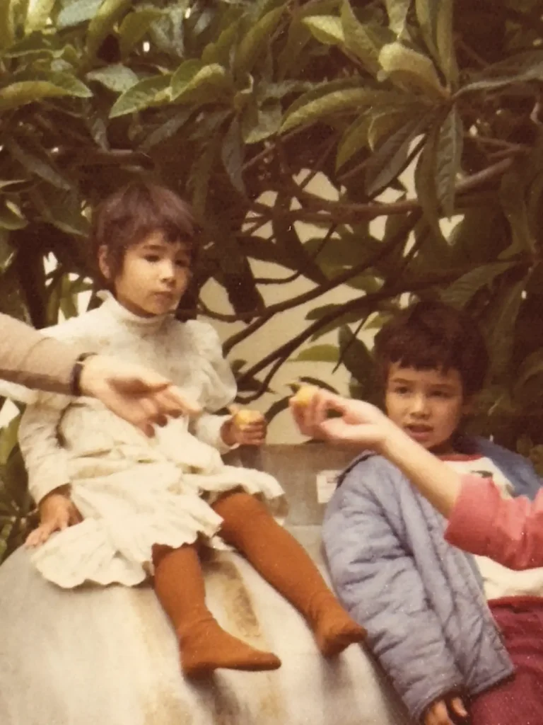 The author and her brother eating loquats from their backyard tree in a vintage photo.