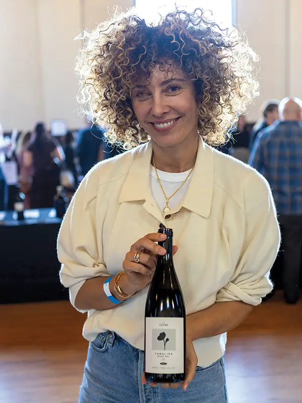 Paula Tabalipa of Tabalipa Wine Company holding a bottle of her wine.