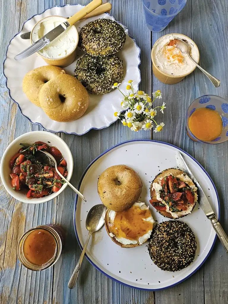 Overhead tablescape with bagels topped with various toppings.