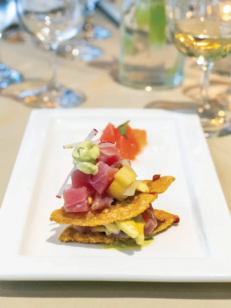 Corn crisp and bluefin tuna with lime, cilantro, ruby grapefruit and Thai basil on a rectangular white serving dish.