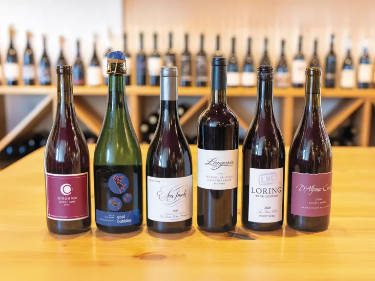 A selection of Lompoc made wines on a counter with blurred wine bottles in the background.