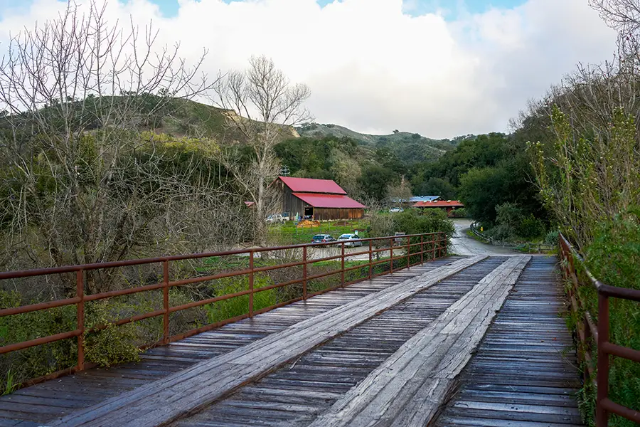 Wooden bridge leading to red roofed Midland School barn.