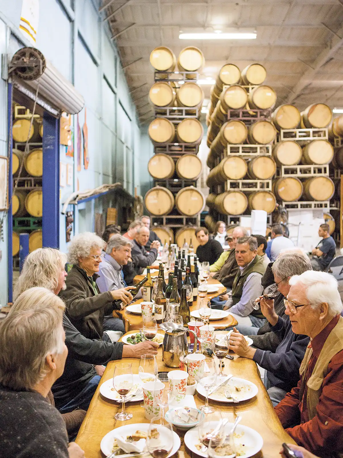 Zaca Mesa alumni gathered around a long dining table in the barrel room.