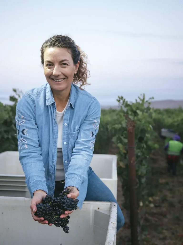 Kira Malone of Pars Fortuna Winery holding a cluster of grapes.