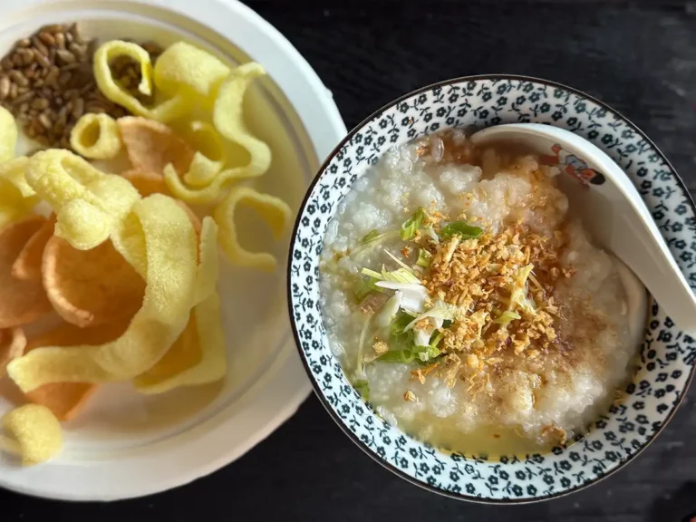 A bowl of basic congee next to a plate of shrimp chips.