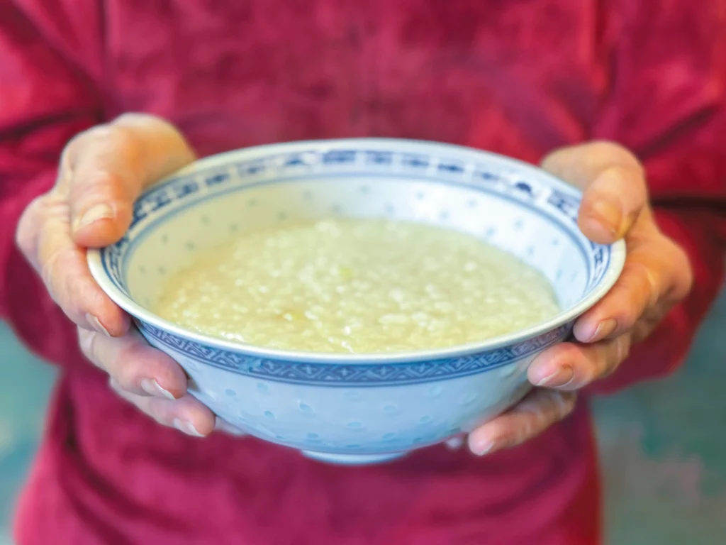 Outstretched hands holding a bowl of congee.