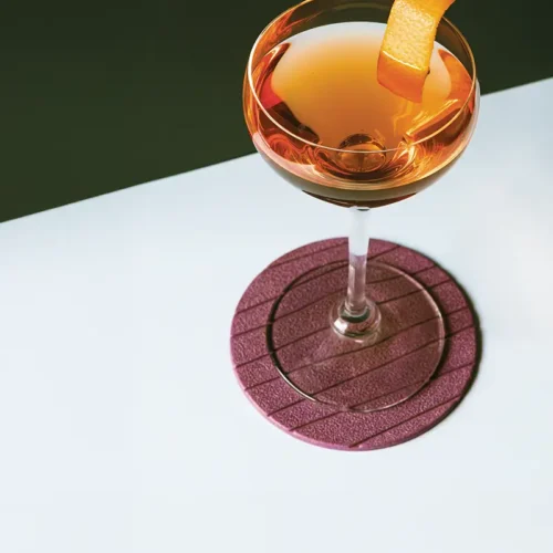 Cocktail coupe with an orange peel garnish against a stark diagonal-divided background.