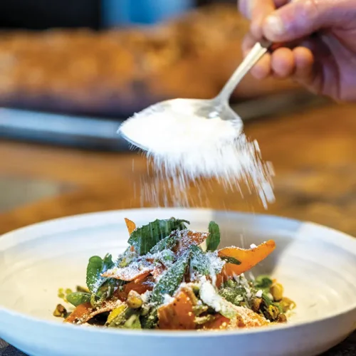 Goat cheese snow rains down on a bowl of Barbareño's Snap Pea and Carrot Salad.