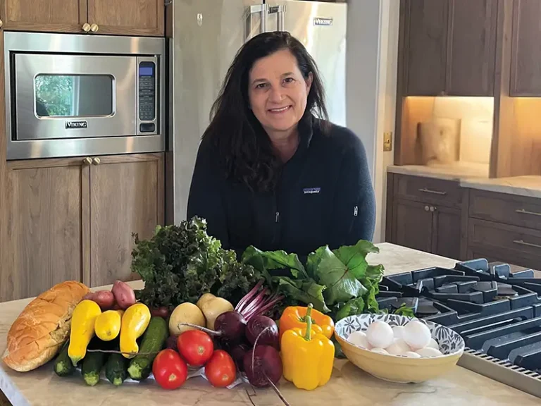 Brenda Browning standing behind a spread of fresh produce in her kitchen.