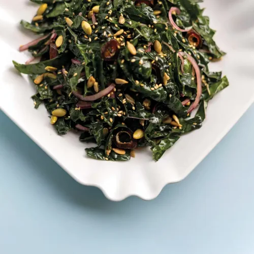 Kale salad in a square white serving bowl.